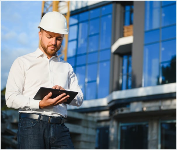 Construction expert with ERP tablet in front of construction site